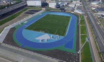 上空から撮影された青色のトラック内にサッカーコートがある陸上競技場の写真