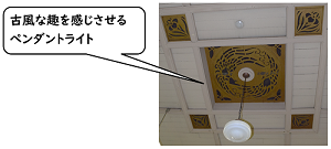 「古風な趣を感じさせるペンライト」鳳凰・蝶・菖蒲の透かし彫りが施された天井の中央にペンダントライトが吊るされている写真