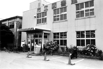 2階建ての建物で、入口の右側に花壇がある市立図書館の白黒写真