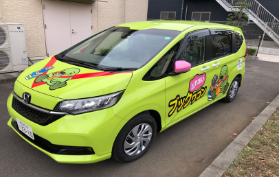 黄緑色の車体にブックワゴンの文字やイラストが貼られた図書館ふれあいブックワゴンのラッピング車両の写真