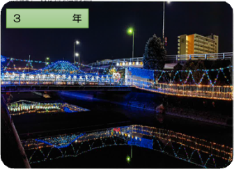青を基調とした色鮮やかなイルミネーションが川の水に反射している様子を写した令和3年の三郷市の写真