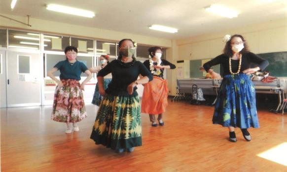 パウスカートを履き、髪飾りや首飾りを付けてダンスの練習をしている5人の女性の写真