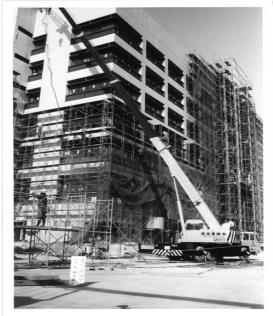 7階建てのビルの前にクレーン車が稼働している、建築中の新庁舎の白黒写真