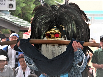 頭に獅子頭をつけた踊り手が紺色の布をかけた刀の鞘を両手で持っている一場面の様子の写真