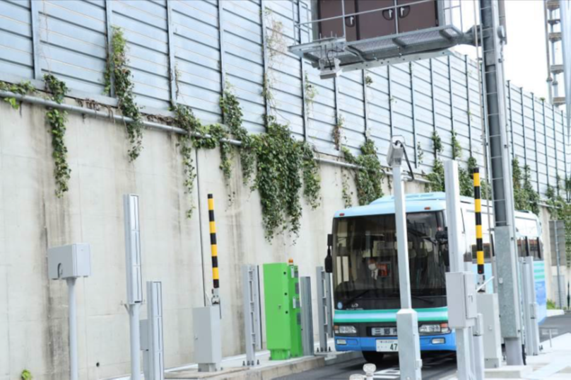 青と緑のラインが入ったバスが 整備後の三郷料金所スマートインターチェンジ(水戸方面への入口)を通過している写真
