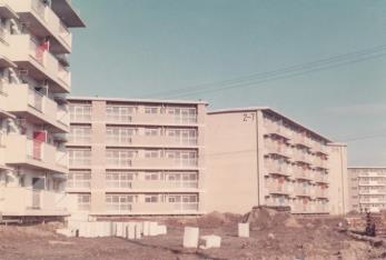 周囲の地面が整備途中の5階建ての団地を下からアップで撮影した写真