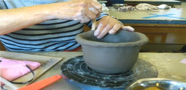 ろくろを回して、壺のような器を作っている女性の手元を写した陶芸の写真