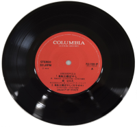 円形で中心部分が朱色でデザインされ曲名が記載されているレコードの写真