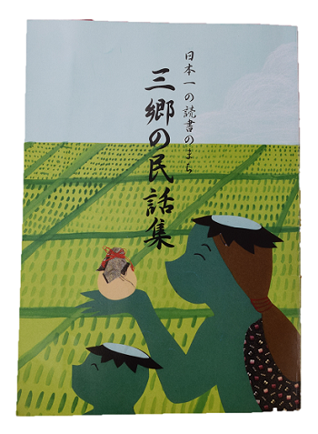 青空の下の田園の前で、2匹のカッパが微笑んでいるイラストが書かれた三郷の民話集表紙写真