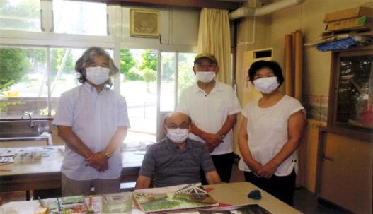 男性が座りその周りを囲むように男性2名と女性1名が立って記念撮影をしている写真