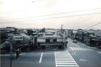 道沿いに商店が並び、横断歩道の線が引かれた交差点を上から撮った白黒写真