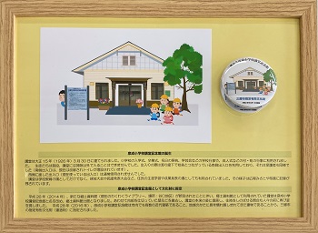 彦成小学校講堂記念館が描かれたイラストと缶バッチの写真