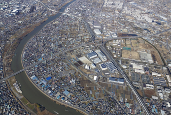 平成25年（2013年）に上空から撮影された、道路が十字に交差し続いており、その周辺に大型の工場が建っている三郷インターチェンジの写真