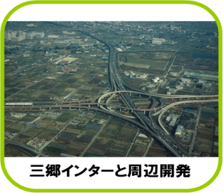 奥にある住宅地や、左右の田畑を通り、上下左右から伸びた高速道路が写真中央で交差しており、周りには大型の施設が点在している、三郷ジャンクションの航空写真（三郷インターと周辺開発のページへリンク）