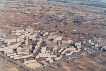 周囲に空き地や田畑が広がる中央に不規則に建ち並んでいる団地を上空から撮影した写真