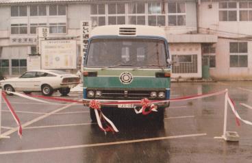 三郷市市章が入っている移動図書館車「ふれあい号」の前に、紅白のテープが張られている出発式の写真