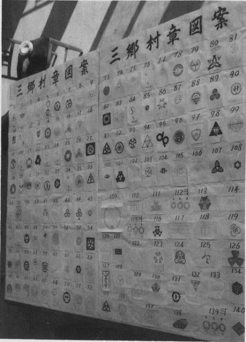 三郷村章図案と書かれた用紙の下部に、様々なデザインの村章図案がずらりと並べられている写真