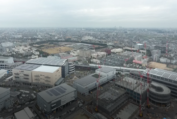 令和3年（2021年）に上空から撮影された、いくつものクレーン車が工事を行い大きな建物が建設されているの三郷インターチェンジ周辺の写真