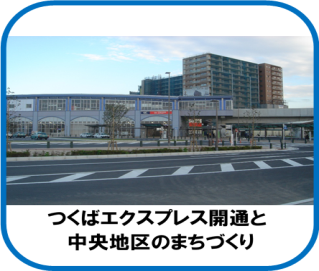 道路の奥にグレーの駅舎と高架鉄道が横に長く見え、背後に高層の建物がいくつか建っている、平成17年（2005年）ごろの三郷中央駅の写真（つくばエクスプレス開通と中央地区のまちづくりのページへリンク）
