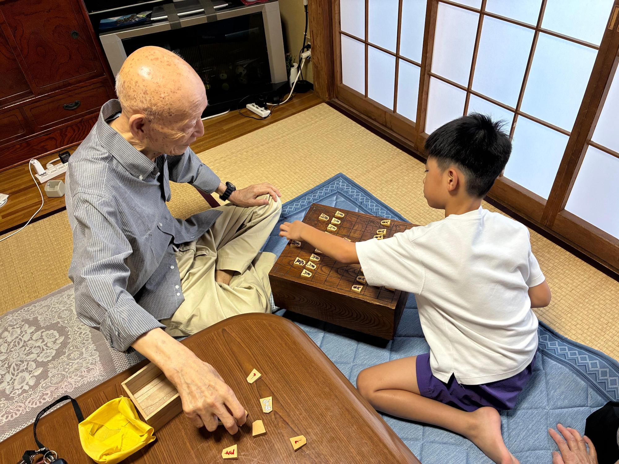 ひいおじいちゃんと孫が将棋をする様子