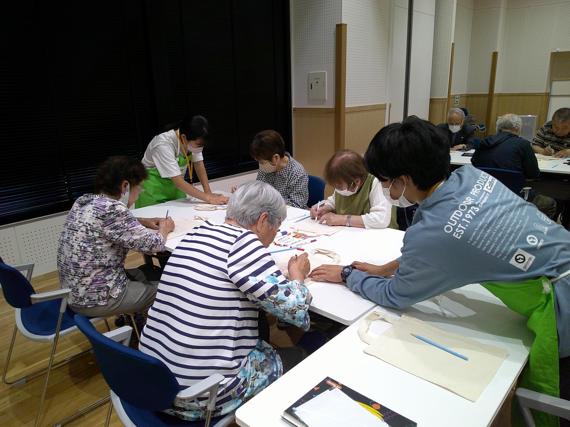 高齢者が絵を描いているのを子どもが手伝っている写真