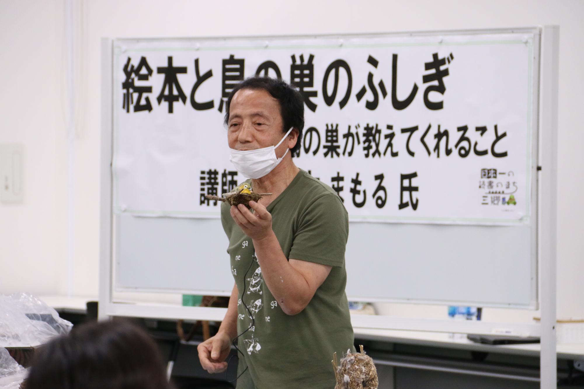 男性が鳥の巣を持って話している写真