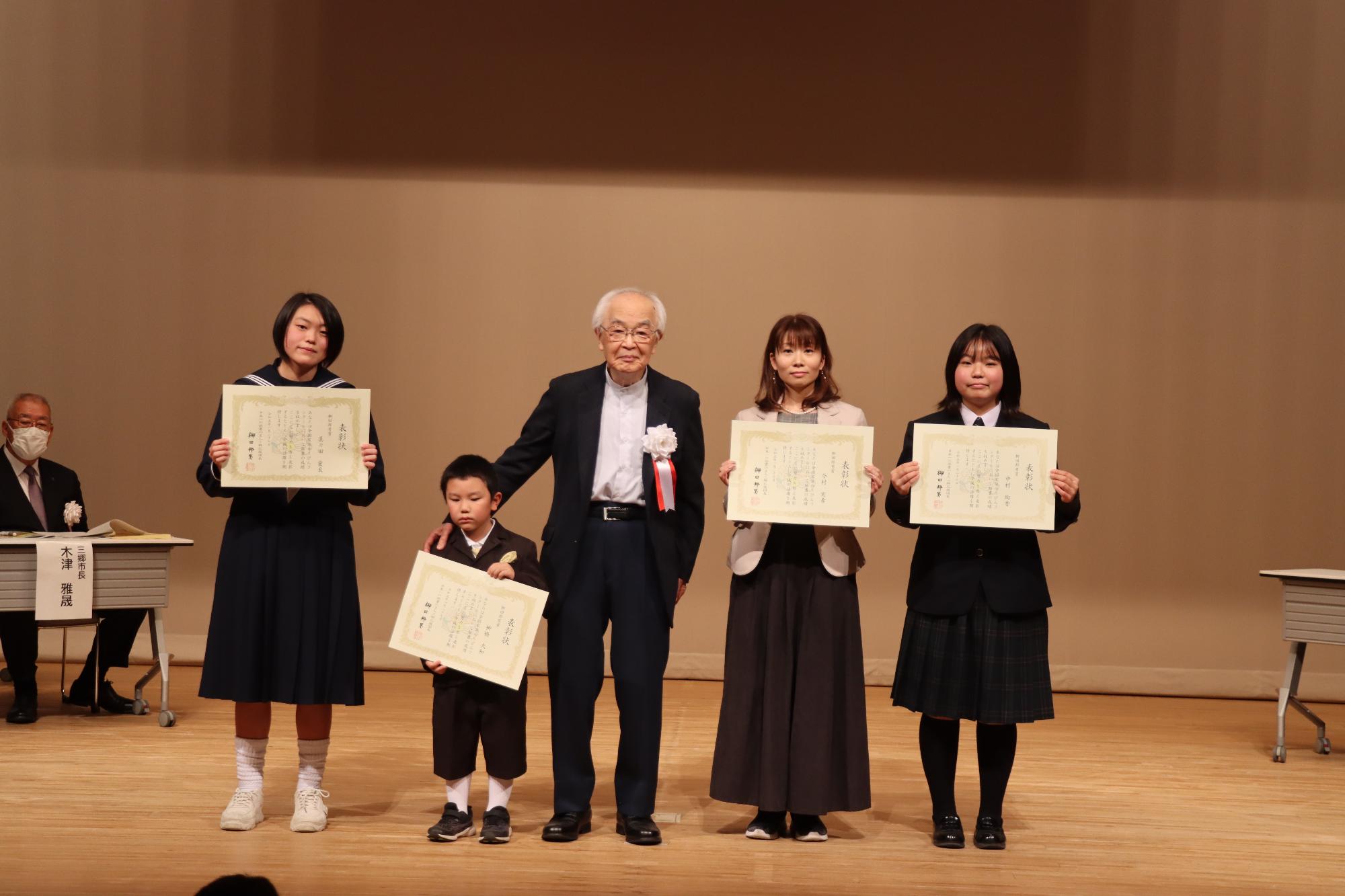 受賞者4人が表彰状を持って立っていてその中央に柳田邦男先生が立っている写真