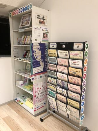 6段の本棚とチラシなどが入ったスタンドが並んで置かれている写真