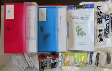 赤、青ファイル、指示書、レジ袋、筆記用具を並べた写真