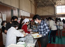 市内ボランティアの皆さんと広野町の方々が協力して盛り付けし、昼食に学校給食を配膳している写真