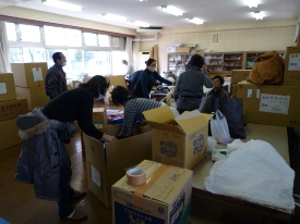 多くの市民から寄せられた支援物資を段ボール箱に分け整理するボランティアのみなさんの写真